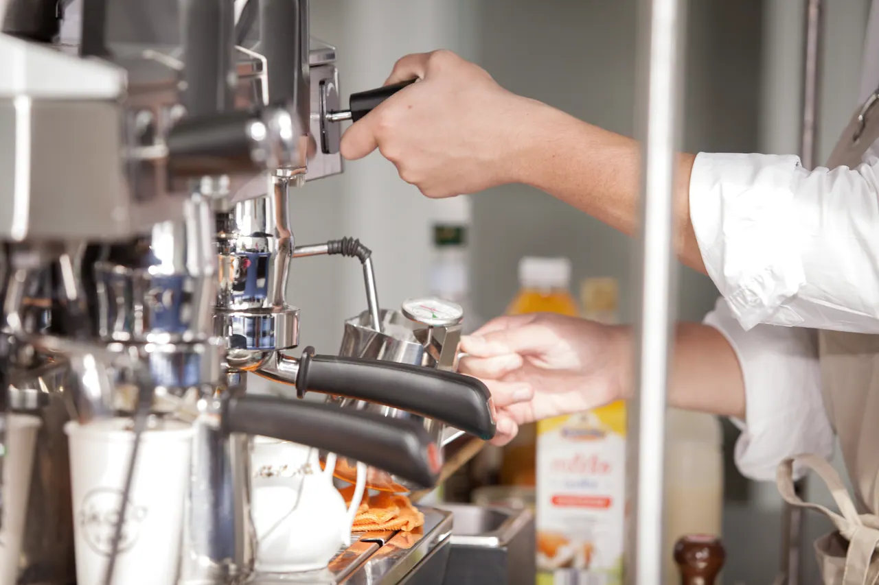Ruce baristy u páky kávovaru na coffee biku