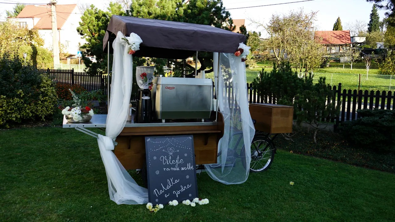 Coffee bike ozdobený tylem a květinami na svatbě na zahradě